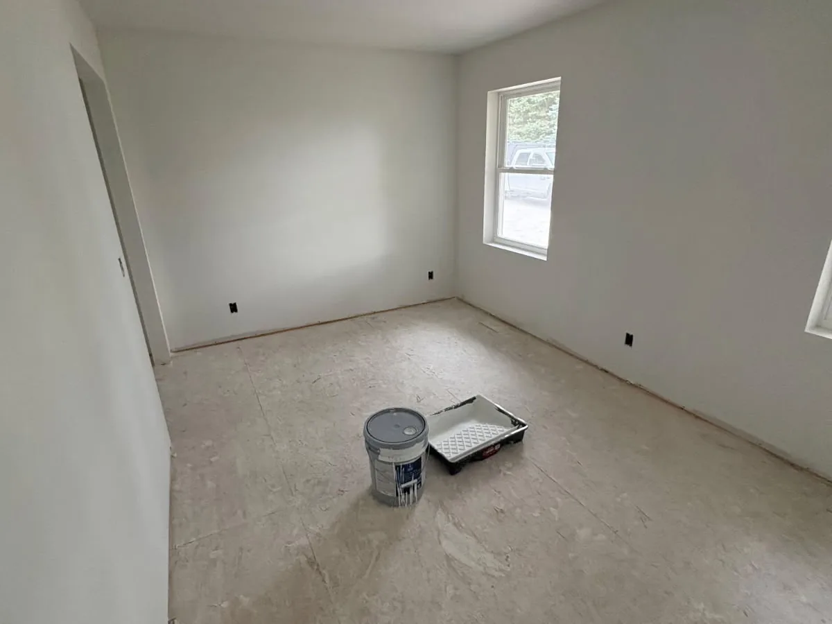 Primed drywall bedroom with a window and corner wall