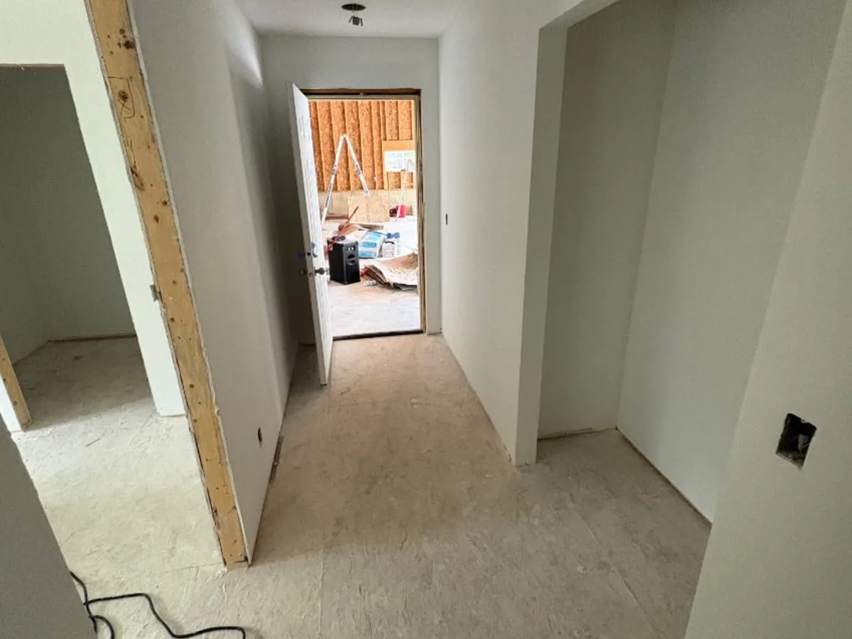 Primed drywall hallway leading to a doorway